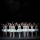 A group of ballerina's in white tutus with their hands in the air.