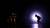 Dancers hold positions on stage in a spotlight