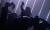 Several dancers appear in different positions, strip lighting appears behind them